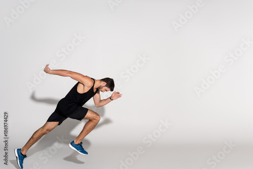 side view of young man running on white