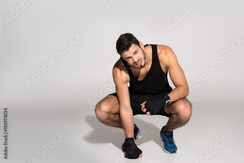 exhausted young fighter sitting on white surface