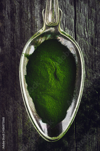 Spoon of chlorella powder on a wooden background