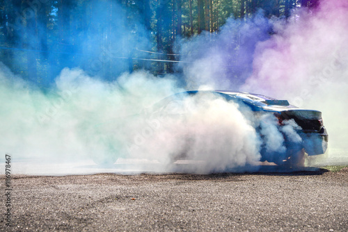 Drift car warming up the tires before start, waiting for race to begin. Blue and purple smoke all around