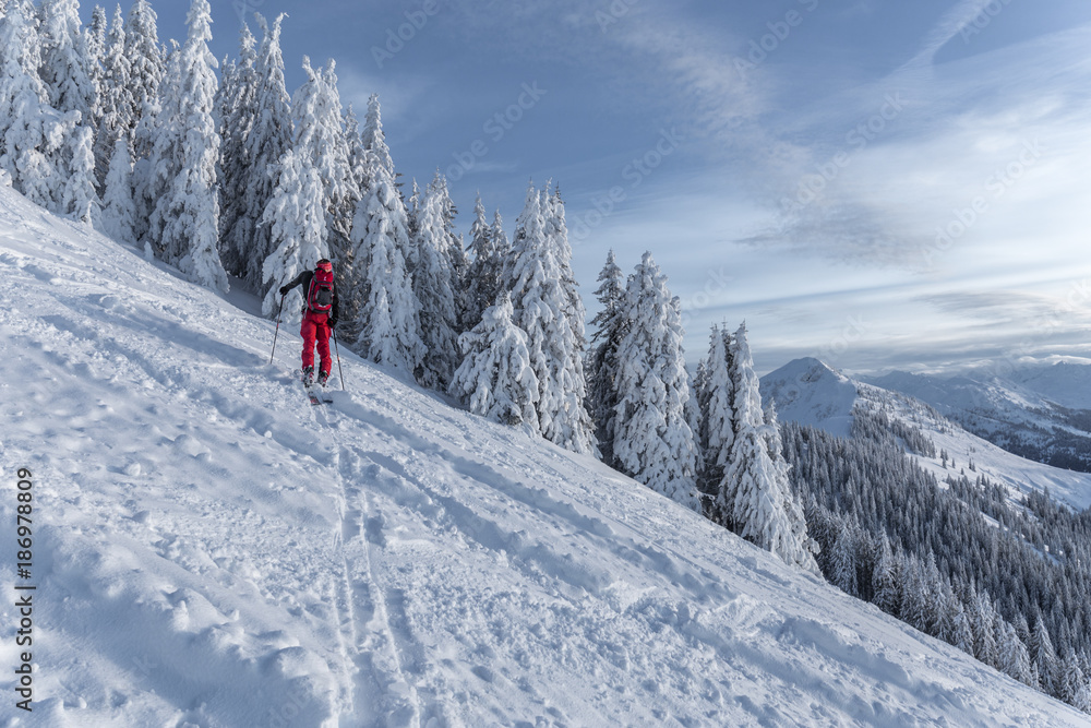 Mann beim Skitouren gehen im Gebirge bei verschneiter Landschaft