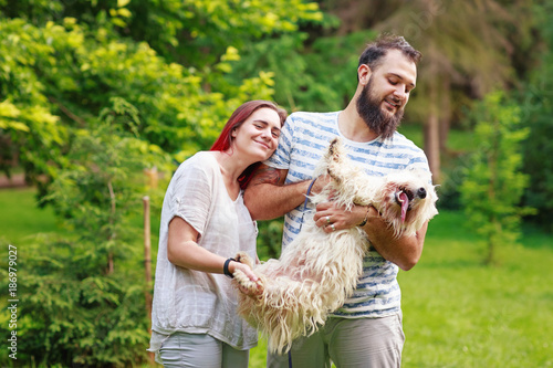 Young smiling woman liying down to a man with dog photo