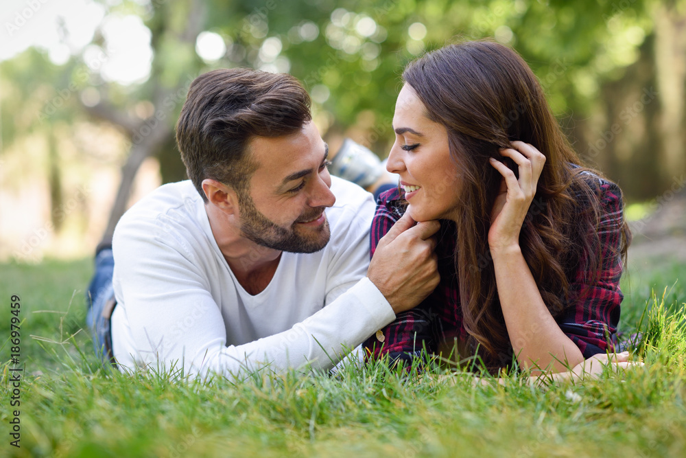 Beautiful young couple laying on grass in an urban park. Beautiful young couple laying on grass in an urban park.