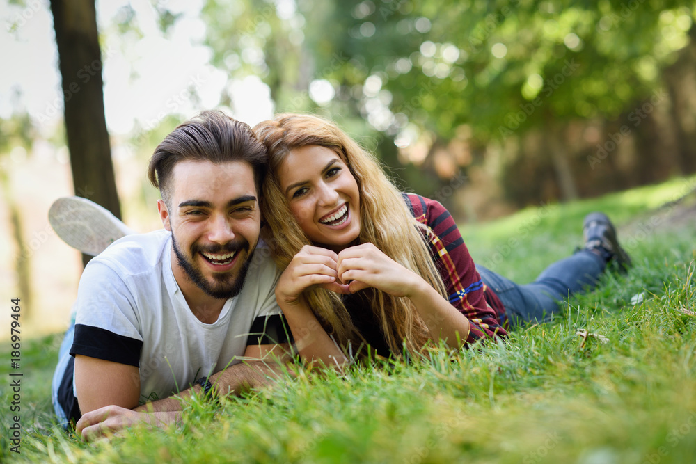 Beautiful young couple laying on grass in an urban park. Beautiful young couple laying on grass in an urban park.