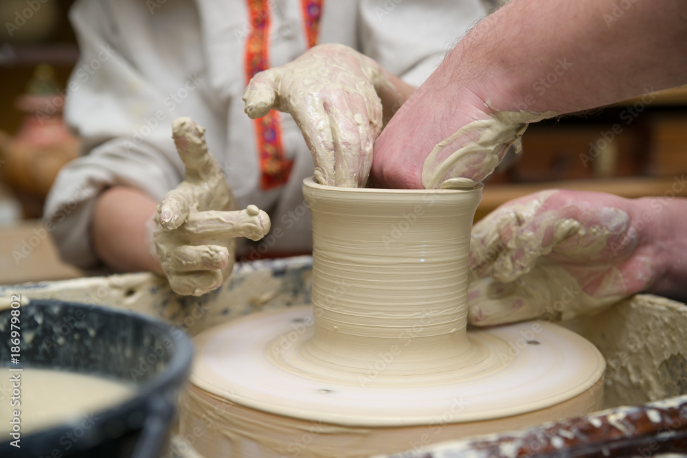 Hands of a potter, creating a pot of clay