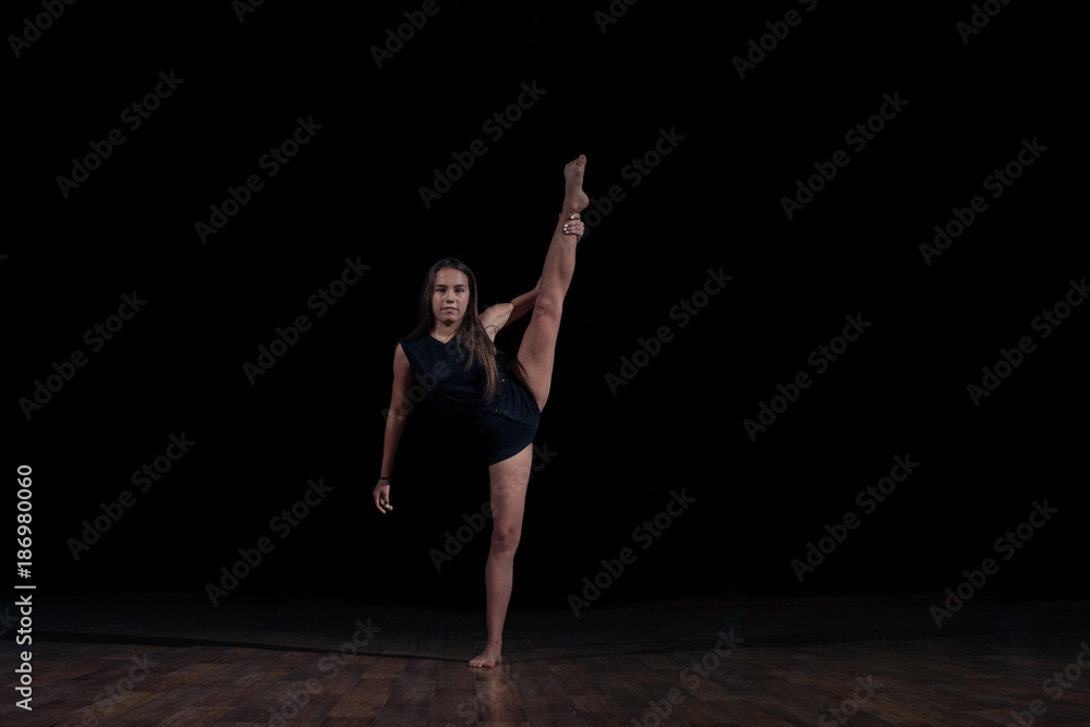 Young gymnast girl isolated on black background doing gymnastic sketch