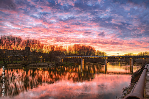 Magical sunset with magenta tones over river and iron bridge