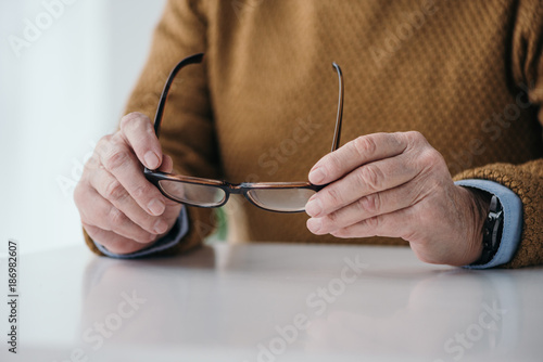 Close-up view of senior man holding eyeglasses