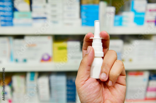 Close up shot pharmacist holding nasal spray medicine at the drugstore.Seasonal health issues