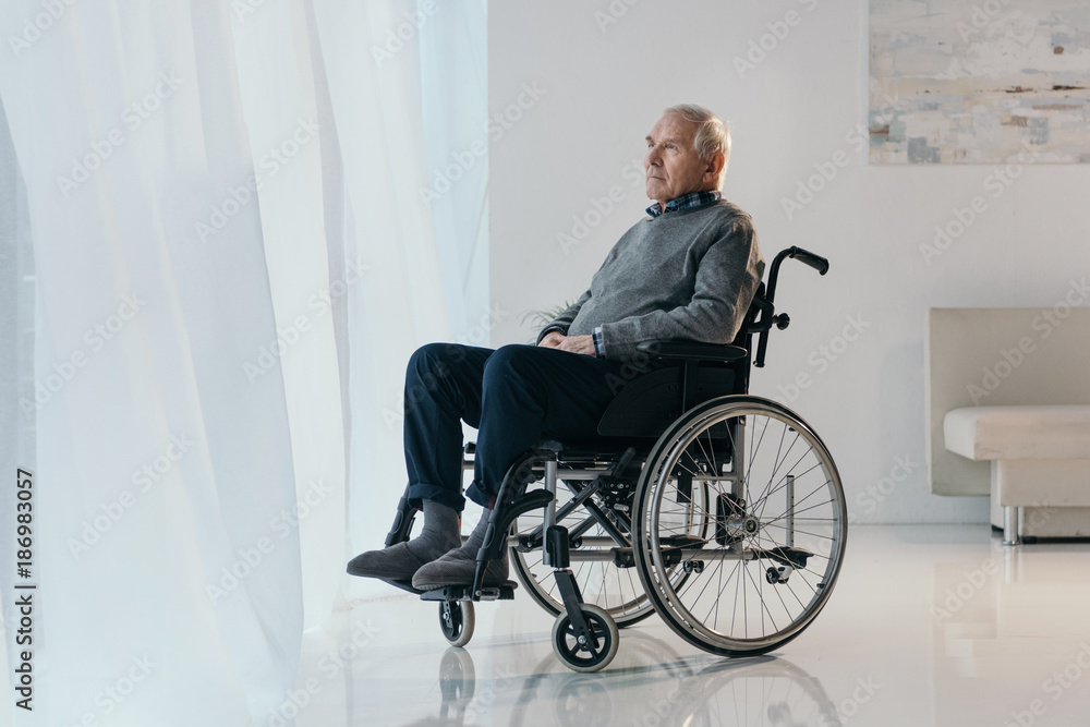 Senior thoughtful man in wheelchair looking in window Senior thoughtful man in wheelchair looking in window