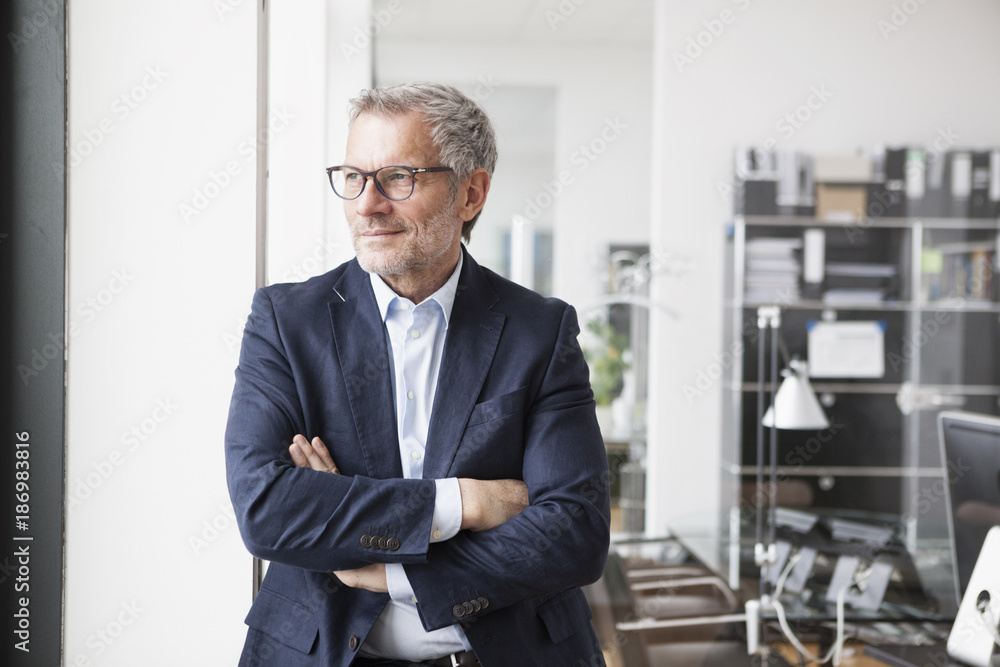Successful businessman standing in his office with arms crossed Successful businessman standing in his office with arms crossed