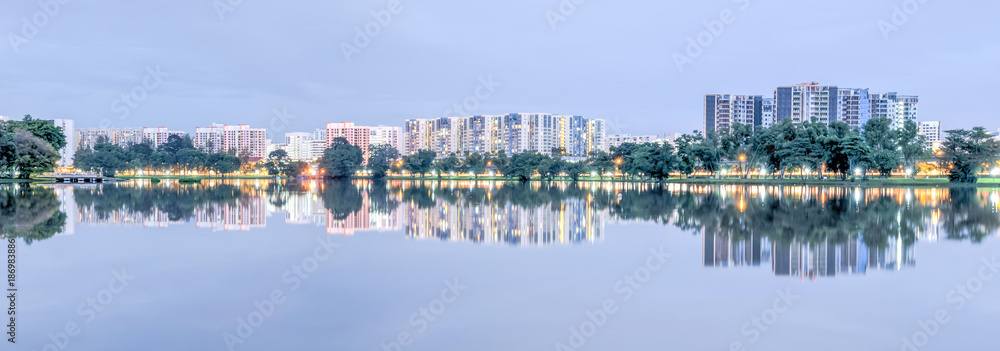 Panorama reflection of new estate HDB housing complex on Jurong Lake neighborhood in Singapore at twilight. Urban concept
