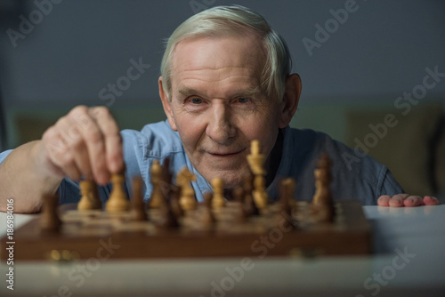 Senior smiling man playing chess board game