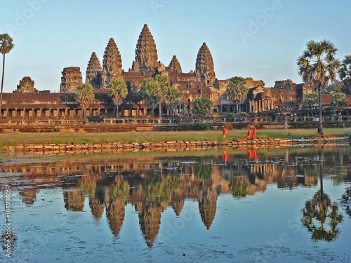 Angkor wat temple while sun set with some of moks standing inf ornt of the lake   photo