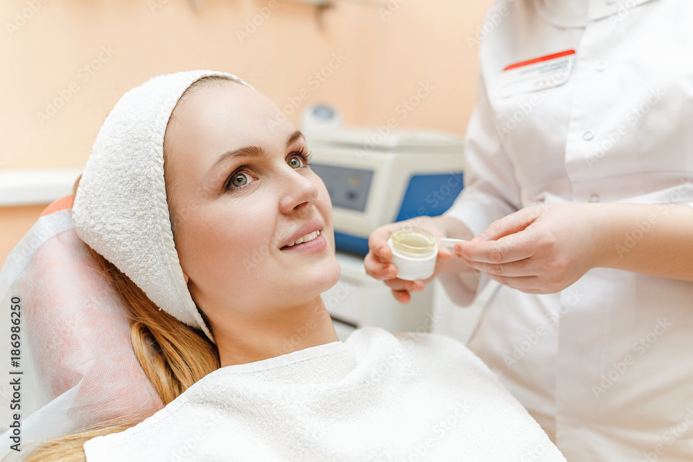 The cosmetologist makes the procedure to her client in beauty clinic