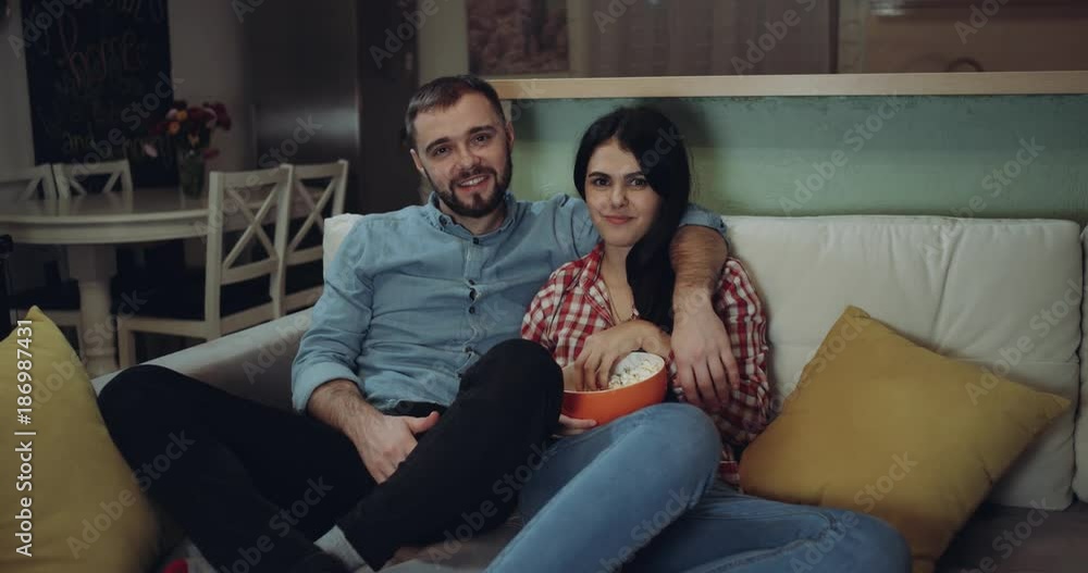Lovely young couple watching tv together and eating the popcorn Lovely young couple watching tv together and eating the popcorn