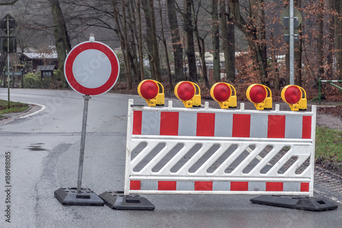Reflective roadblock or construction site lock with signal lamp on a road. Red and white street barricade.