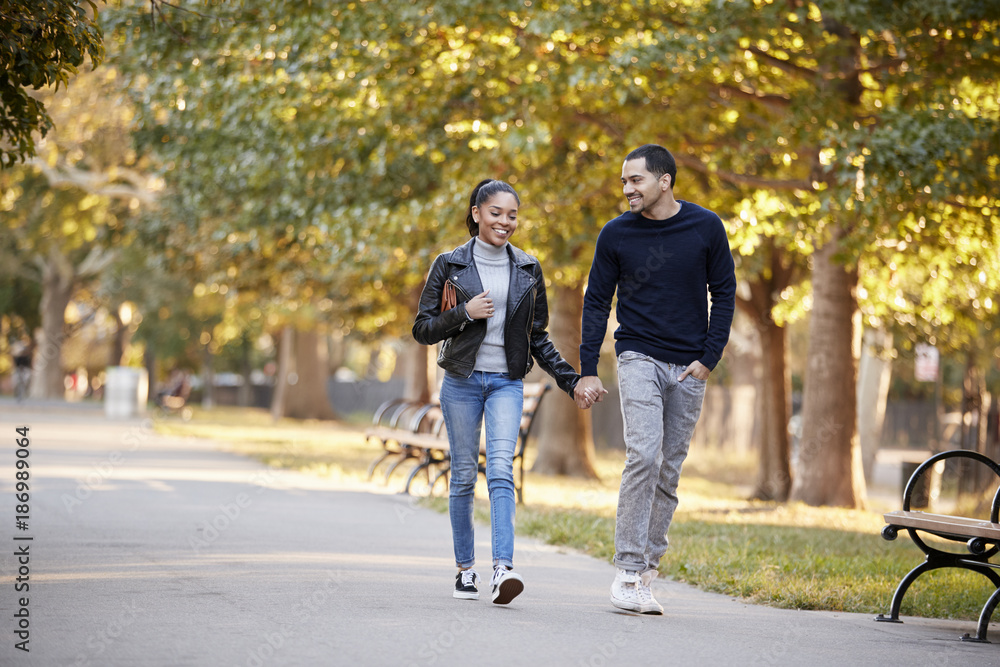 Young Hispanic couple walking hand in hand in Brooklyn park Young Hispanic couple walking hand in hand in Brooklyn park