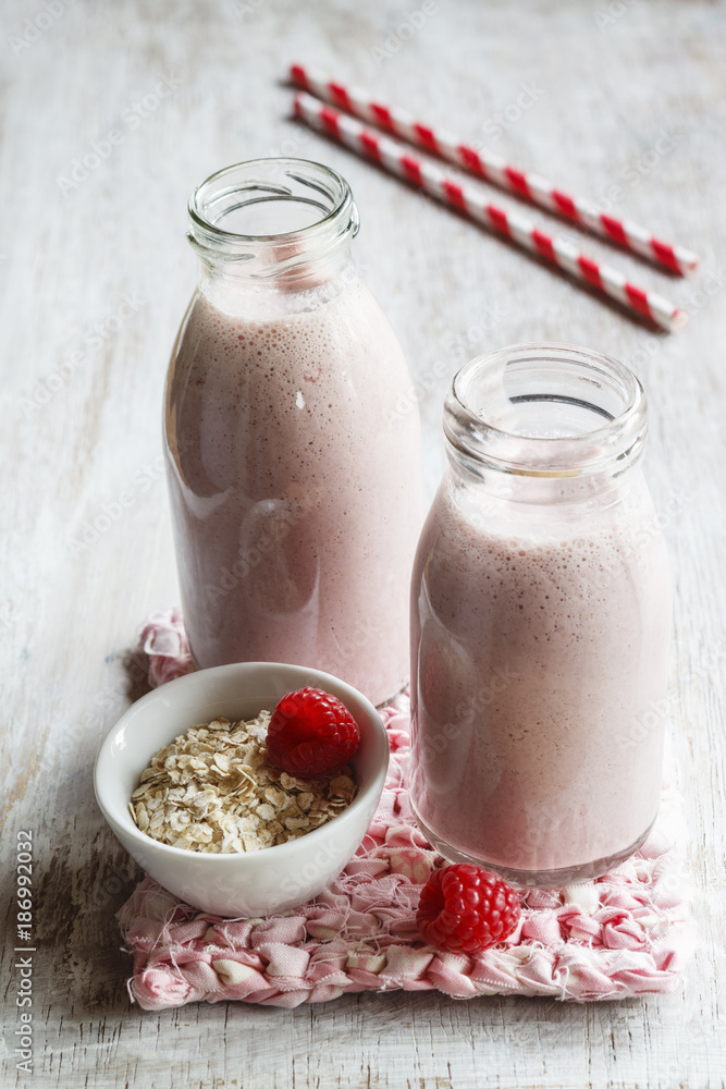 Glass bottles of raspberry milkshakes with oat flakes and basil Glass bottles of raspberry milkshakes with oat flakes and basil