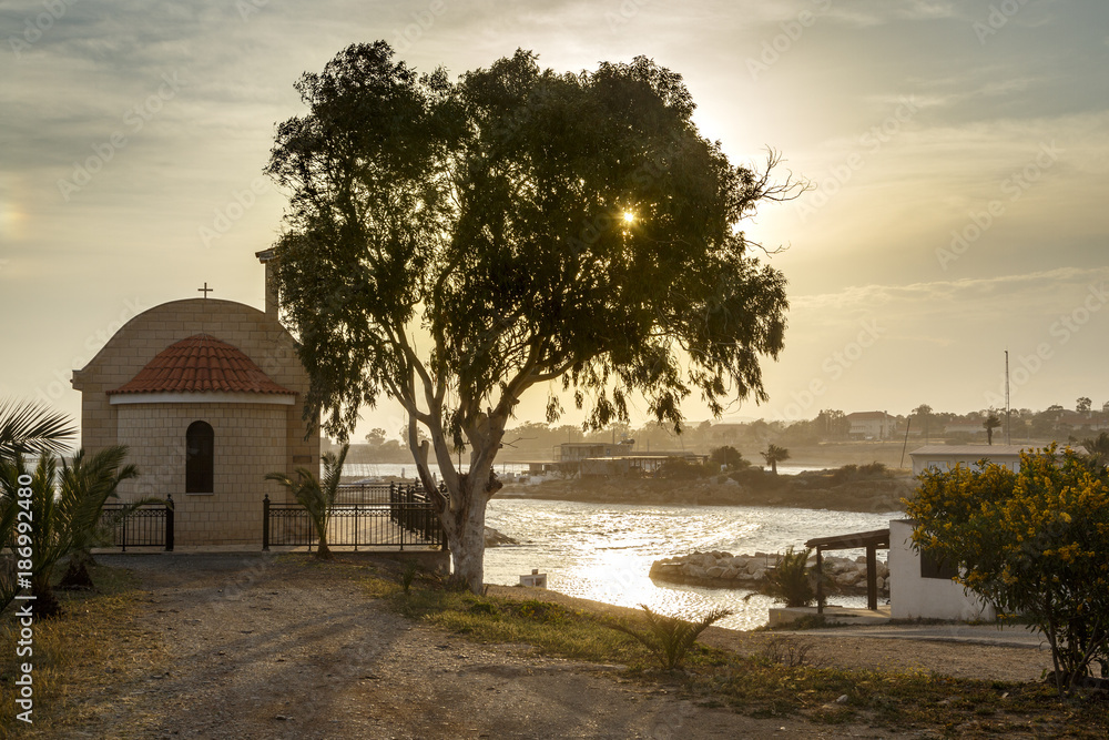 Sunset. Old chapel on the shore of the bay in the Mediterranean Sea.