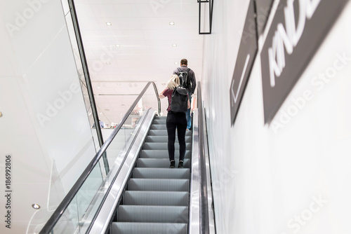 Young woman and man on escalator in store.