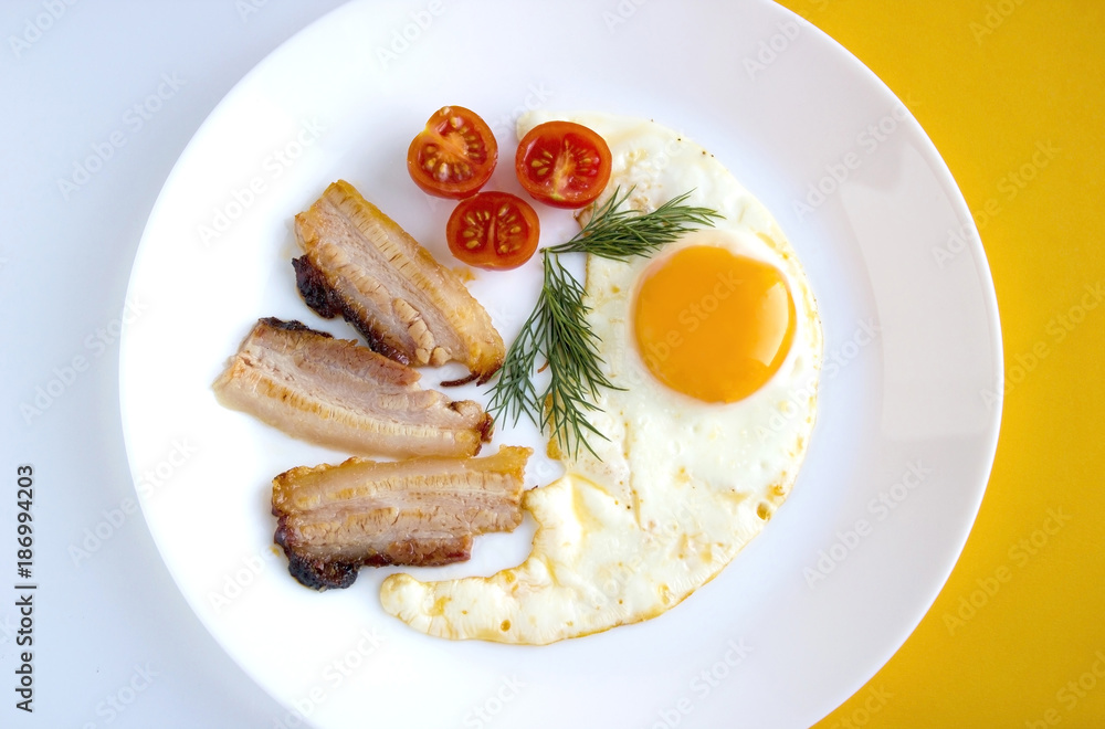 Fried eggs with tomatoes, bacon and dill. Delicious and healthy breakfast оn a white plate.