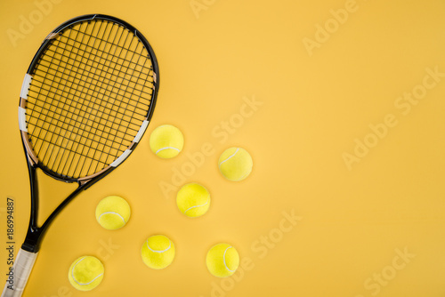 Tennis racket with balls isolated on yellow © LIGHTFIELD STUDIOS