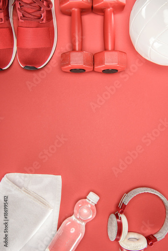 Sports equipment with shoes, dumbbells, ball and headphones isolated on red