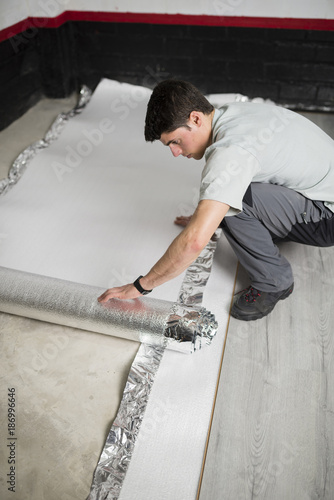 Young man placing a insulating material for a laminate flooring