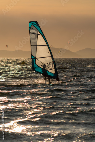 Sunset over the sea or ocean and extreme freestyle sport windsurfing