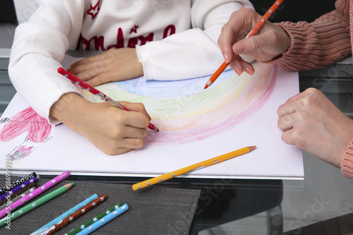 Mother and little daughter drawing a rainbow, partial view