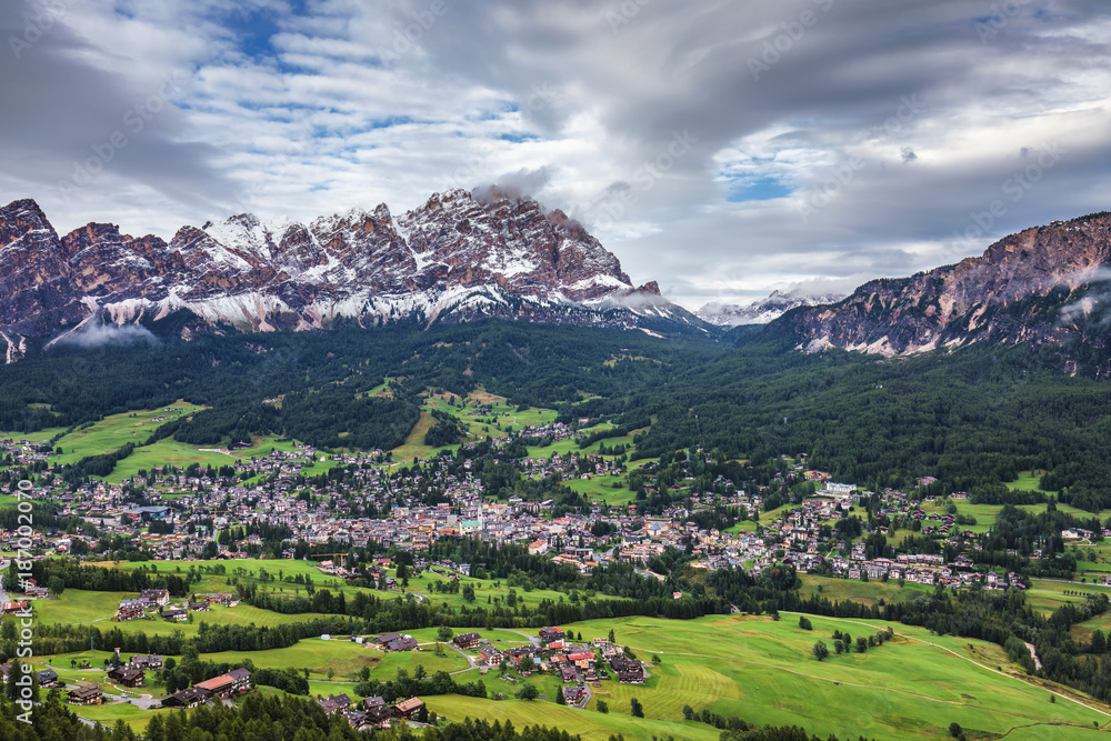 Cortina d'Ampezzo town panoramic view with alpine green landscape and massive Dolomites Alps in the background. Province of Belluno, South Tyrol, Italy. Cortina d'Ampezzo town panoramic view with alpine green landscape and massive Dolomites Alps in the background. Province of Belluno, South Tyrol, Italy.
