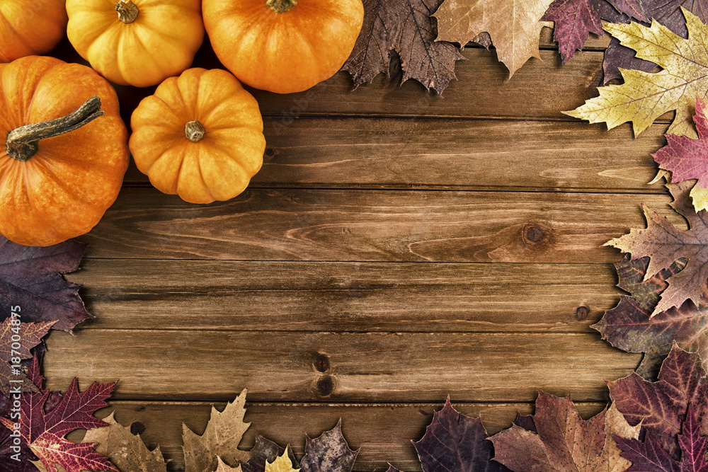 Pumpkins with fall leaves over wooden background. Top view. Pumpkins with fall leaves over wooden background. Top view.