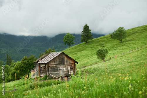 Summer landscape with village house at mountains in cloudy weather.