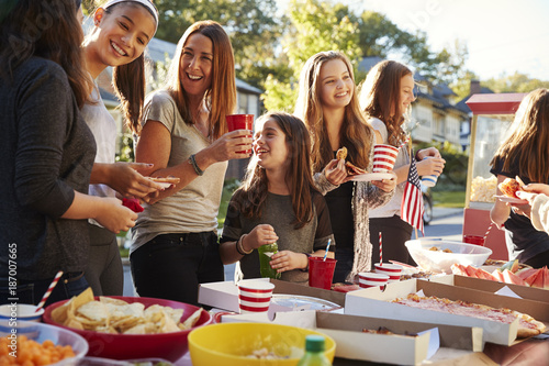 Girls stand talking at a block party food table, close up