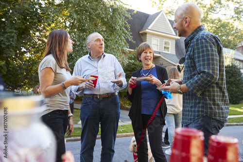 Middle aged and senior neighbours talking at a block party photo