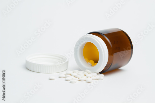 Open medical container with yellow vitamins . Yellow vitamins on white background . Medicines are prepared to patients