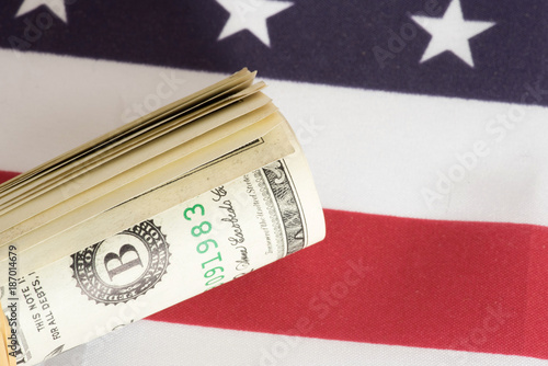 Flagge von USA und eine Geldrolle mit Dollar Geldscheinen