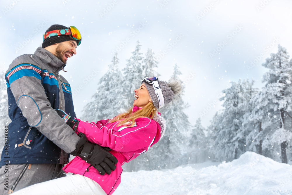 Man and woman having fun in snowy nature on mountain