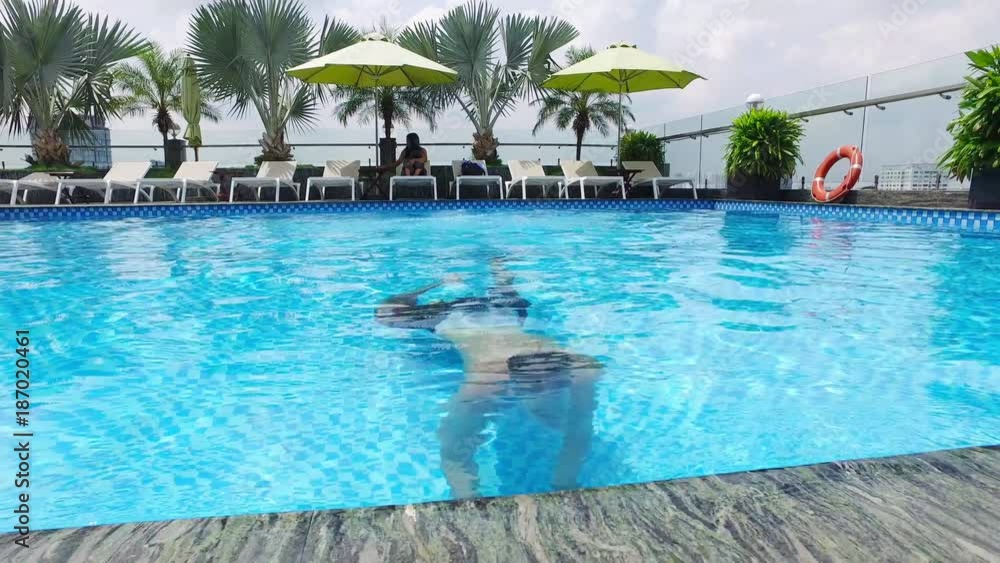 HO CHI MINH CITY, VIETNAM – MAY, 2016 : Video shot of man diving and swimming in pool on a sunny day in hotel HO CHI MINH CITY, VIETNAM – MAY, 2016 : Video shot of man diving and swimming in pool on a sunny day in hotel