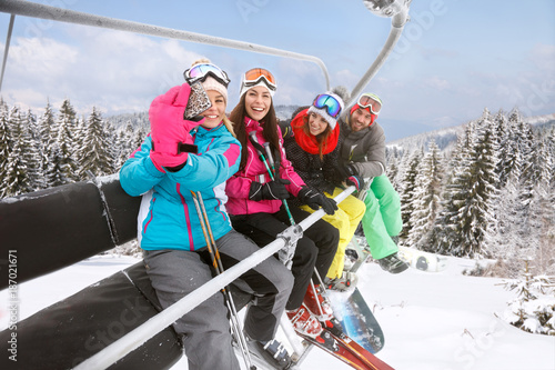 Female making selfie with friends in ski lift