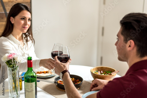 Happy young couple eating and drinking wine at home