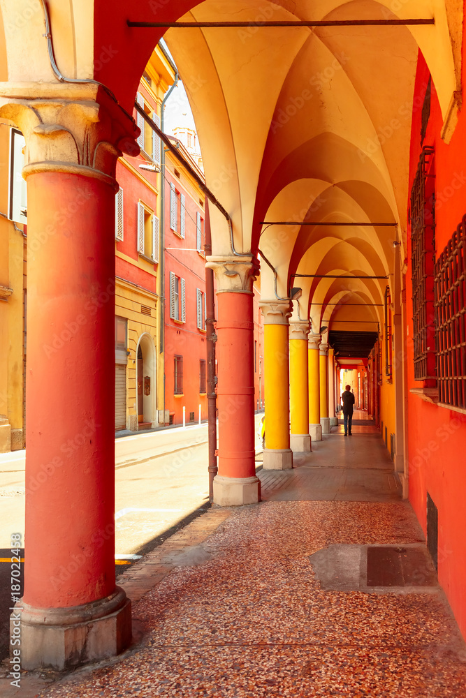 Fototapeta premium Medieval street portico with bright colored houses in the Old Town in the sunny day, Bologna, Emilia-Romagna, Italy