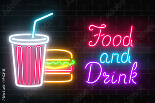 Neon food and drink glowing signboard on a dark brick wall background. Plastic cup of beverage and burger signs.