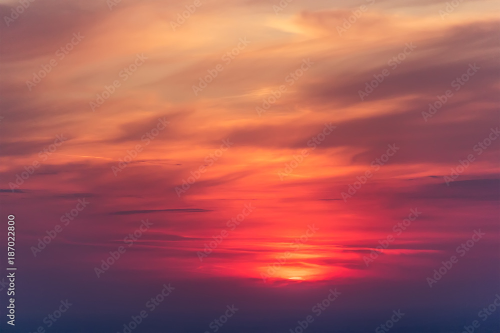 Beautiful colorful cloudscape with a red sun at dusk