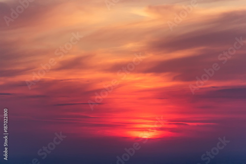 Beautiful colorful cloudscape with a red sun at dusk