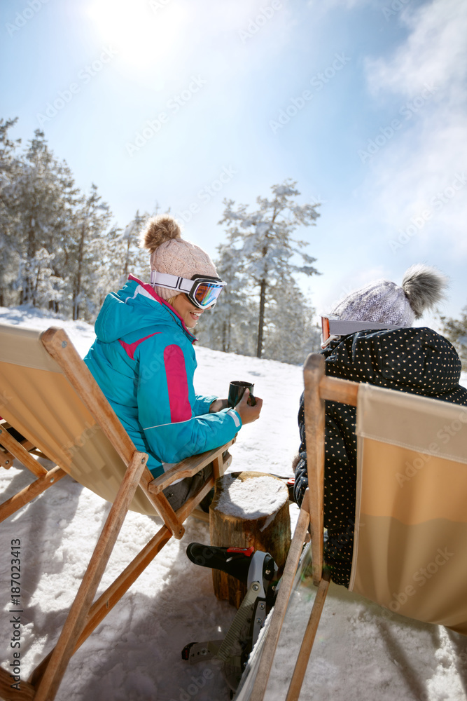 Two female in sun bed talking and resting from skiing, back view Two female in sun bed talking and resting from skiing, back view