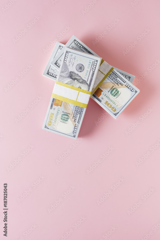 Overhead view of stack of 100 dollar bills on pink background ...