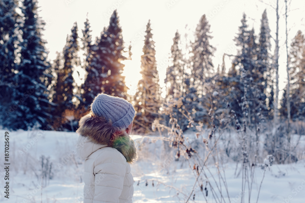 portrait of a girl in profile in the winter forest at sunset