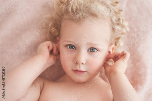 Portrait of a cute little girl touching her ears photo